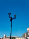 Old vintage black decorative lantern with clear glass on pillar. Three street lamps on one pole. Sunny blue sky gradient Royalty Free Stock Photo