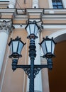 Old vintage black decorative lantern with white glass on pillar against the background of a beautiful building in Saint Petersburg Royalty Free Stock Photo
