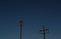 Old vintage black decorative lanterns with glass on pillars. Three street lamps on two pole in sunset light. Blue sky gradient.