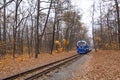 Old vintage blue railway train on the track rails front view. Railroad single track through the woods in autumn. Fall landscape Royalty Free Stock Photo