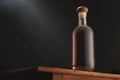 Old vintage bottle of whiskey or brandy, rum or cognac with dust on rustic table, black background. Alcohol drink, no label. Copy