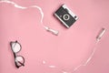 Old vintage camera, glasses and two small glass bottles from which spilled white liquid on pink studio background. Close Royalty Free Stock Photo