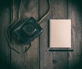 Old vintage camera in a leather case and a notepad with a wooden black pencil Royalty Free Stock Photo