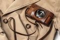 Old vintage camera with 50mm lens in brown leather case on beige trench coat. Royalty Free Stock Photo