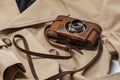 Old vintage camera with 50mm lens in brown leather case on beige trench coat. Royalty Free Stock Photo