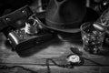 Old vintage cinematic noir scene, detective`s desk with a hat, telephone, camera, portable cassette recorder, and whisky