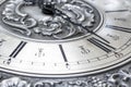 Old vintage clock with metal dial and floral embossed pattern close-up. Black clock hands indicating a time of 6 hours. Beautiful Royalty Free Stock Photo