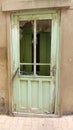 Old vintage door broken wooden with four windows at grey exterior stucco ancient crack wall