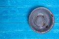 Old vintage enameled rusty bowl on blue wooden desk.