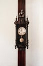 Old vintage grandfather wooden wall clock hanging on wood pillar Royalty Free Stock Photo