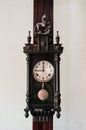 Old vintage grandfather wooden wall clock hanging on wood pillar Royalty Free Stock Photo