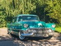 Old vintage green Cadillac car driving in autumn weather