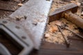 Old vintage hammer, wood saw, nails and sawdust on a wooden background, close-up, selective focus Royalty Free Stock Photo