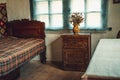 Old vintage historic room with wooden bed, bedside table and vase of flowers Royalty Free Stock Photo