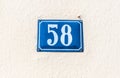 Old vintage house address blue metal plate number 58 fifty eight on the plaster facade of abandoned home exterior wall on the stre Royalty Free Stock Photo