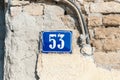 Old vintage house address blue metal plate number 53 fifty three on the plaster facade of abandoned home exterior wall on the stre Royalty Free Stock Photo
