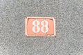 Old vintage house address metal number 88 eighty-eight on the plaster facade of abandoned home exterior wall on the street side Royalty Free Stock Photo