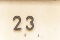 Old vintage house address metal number 23 on the plaster facade of abandoned home exterior wall on the street side