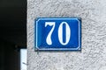 Old vintage house address metal number 70 seventy on the plaster facade of abandoned home exterior wall on the street side