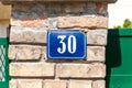 Old vintage house address metal number 30 thirty on the brick facade of abandoned home exterior wall on the street side Royalty Free Stock Photo
