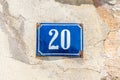 Old vintage house address metal number 20 twenty on the plaster facade of abandoned home exterior wall on the street side