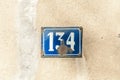 Old vintage house address metal plate number 134 one hundred thirty four on the plaster facade of abandoned home exterior wall Royalty Free Stock Photo