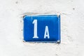 Old vintage house address metal plate number 1 A on the plaster facade of abandoned home exterior wall on the street side