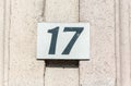 Old vintage house address metal plate number 17 seventeen on the plaster facade of abandoned home exterior wall on the street side