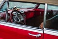 Old vintage interior of a red car with steering wheel and cockpit. Retro styled image of an old classic car inside