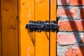 Old vintage iron lock on wooden yellow door on red brick wall background Royalty Free Stock Photo