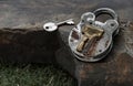 Old vintage iron padlock with key on Huge stone over green grass background