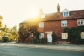 Old vintage medieval beautiful stone british house with tile roof and bright windows, a flowering rose garden near the asphalt Royalty Free Stock Photo