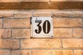 Old vintage minimalist street adress number sign with number 30 on the facade of the brick house wall Royalty Free Stock Photo