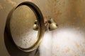 Old vintage mirror and wall lamp in gray on a wooden base, on a silver-gold wall background close up photo. Royalty Free Stock Photo