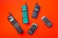 Old vintage mobile cell phones on red orange background