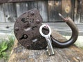 Old vintage padlock. The lock of the lock is open. Nearby is the key to the padlock. Against the background of an old wooden shed. Royalty Free Stock Photo