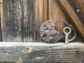 Old vintage padlock. The lock of the lock is open. Nearby is the key to the padlock. Against the background of an old wooden shed. Royalty Free Stock Photo