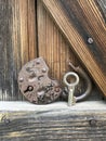 Old vintage padlock. The lock of the lock is open. Nearby is the key to the padlock. Against the background of an old wooden shed. Royalty Free Stock Photo