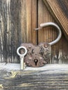 Old vintage padlock. The lock of the lock is open. Nearby is the key to the padlock. Against the background of an old wooden shed. Royalty Free Stock Photo