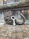 Old vintage padlock. The lock of the lock is open. Nearby is the key to the padlock. Against the background of an old wooden shed. Royalty Free Stock Photo