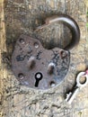 Old vintage padlock. The lock of the lock is open. Nearby is the key to the padlock. Against the background of an old wooden shed. Royalty Free Stock Photo