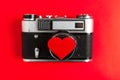 Old vintage photo camera with red heart on it. red background.for decor and design. valentines greeting card.