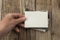 Old vintage photo template mockup in hands on wooden background. Empty retro card, textured paper Royalty Free Stock Photo