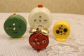 Old vintage red alarm clock with two bells on a background of yellow, white and green alarm clocks of different sizes on a white v