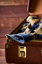 Old vintage, retro open suitcase with man`s checkered shirt on dark background. Travel concept. Vertical Royalty Free Stock Photo