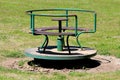 Old vintage retro partially rusted outdoor public playground equipment made of metal and cracked wood in shape of roundabout