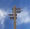 Old wooden road sign with four arrows over sky