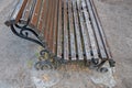Old vintage shabby bench cemented into ground with metal wrought-iron sides with spirals and curls and riveted wooden brown slats