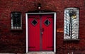 Old vintage style house exterior with red brick walls, window guards and red wooden door Royalty Free Stock Photo