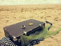 Old vintage suitcase for travel and family vacations lies on the beach. Sea shore ocean. Photo in a trendy retro style Royalty Free Stock Photo